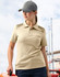 A model wears a beige polo shirt with textured detailing on the shoulders, paired with a grey cap.