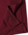A close-up of the hem and fabric of a burgundy polo shirt, featuring a logo on one side.