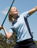 A light blue and navy polo shirt with a collar, featuring a logo, worn by a woman swinging a sports implement outdoors.
