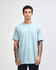 A light blue unisex short sleeve t-shirt displayed on a model. The shirt has a logo branding.