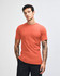 An orange unisex short sleeve t-shirt displayed on a model with long hair, featuring a logo.