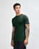 An unisex fine jersey short sleeve t-shirt in dark green, displayed on a model from the side.