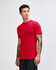 A red unisex short sleeve t-shirt displayed on a model from the side, featuring a branding logo.
