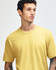 A model wearing a yellow American Apparel Fine Jersey short sleeve t-shirt. The shirt features a logo.