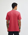 A unisex short sleeve t-shirt in a deep red colour, featuring a simple design and a logo on the back.