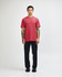 A unisex CVC short sleeve t-shirt in red, paired with black cargo pants. The model displays a casual pose.