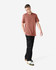 A unisex short sleeve t-shirt in rust colour, paired with black cargo pants. The model is standing with one hand in his pocket.