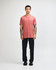 A unisex short sleeve t-shirt in rust colour, paired with black cargo pants. The model is standing with one hand in his pocket.