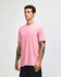 A pink unisex CVC short sleeve T-shirt displayed on a model. The shirt has a simple design and a logo.