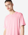 A unisex short sleeve T-shirt in pink, featuring a simple design and a logo.