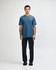 A unisex CVC short sleeve t-shirt in a blue shade, paired with black cargo pants. The model stands casually.