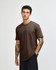 A unisex short sleeve T-shirt in brown, displayed on a model standing against a plain background. It features a logo.