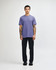 A unisex short sleeve t-shirt in purple, worn by a model with black pants and sneakers, featuring a logo.