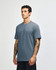 A unisex short sleeve t-shirt in a blue colour, featuring a logo on the front. The model stands against a light background.