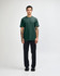 A green unisex CVC short sleeve T-shirt displayed on a model wearing black cargo pants and sneakers.
