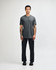 A grey unisex CVC short sleeve t-shirt displayed on a model, paired with black trousers, and featuring a logo.