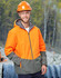 A Hi-Vis quilted two-tone safety jacket in orange and grey, worn by a man in a hard hat and safety glasses, outdoors.