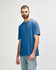 A blue Gildan Softstyle adult t-shirt is displayed on a model, featuring a simple design and relaxed fit.