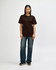 A brown Gildan Softstyle adult t-shirt displayed on a model, paired with light blue jeans and white shoes.