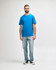 A man wearing a bright blue Gildan Softstyle adult midweight T-shirt and black jeans, with a casual stance.