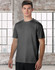 A men's short sleeve tee in grey, featuring a minimal design and a logo. The model stands against a large window background.