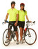 A unisex cycling top in bright yellow, worn by two models with bicycles, set against a plain background.