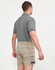Unisex cotton stretch drill short work shorts in beige, paired with a grey polo shirt, shown from the back.