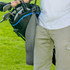 A grey waffle golf towel attached to a golf bag, held by a person. The bag is black with blue accents.