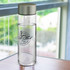 A drink bottle with a clear body and a silver lid, featuring a logo on the surface.