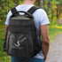 A black cooler backpack with a logo, carried on a person's back, set in a natural outdoor environment.