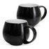 A drinkware set featuring two black coffee mugs with smooth finishes and white interiors. Each mug has a curved shape and handle.