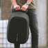 A person holds a sleek, black Bobby Hero Backpack with a minimalist design, featuring a logo on the front.