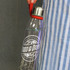A drink bottle with a transparent glass body, silver lid, and a red carrying strap, featuring a branding logo.