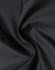 A close-up of lightweight nylon fabric in black, showing a smooth, waterproof texture. There is a logo visible.