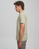 A light green men’s premium cotton t-shirt displayed on a model, viewed from the side. The shirt has a logo on it.