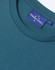 A close-up of a teal women's premium cotton t-shirt featuring a round neckline and a stitched label.