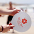 A paddle ball game featuring a large, white paddle with a red logo and a small ball, set against a beach background.