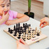 A compact travel chess set with wooden pieces in black and cream, displayed on a folding board.