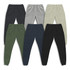 A collection of unisex sweatpants in six colours: grey, black, navy, olive green, beige, and dark grey, featuring a logo.