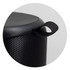 A black Bluetooth speaker featuring a textured surface and a carry strap. The design is compact and cylindrical.