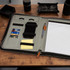A black Nirvana Portfolio featuring card slots, a phone holder, sticky notes, and a pen, with a notepad inside.