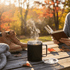A black coffee mug with steam rising, set on a wooden table with autumn leaves. Nearby, there are boots and a person reading.
