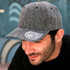 A grey cap with a mid visor and a logo on the brim, featuring a textured fabric design.