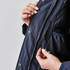 A close-up of a navy puffer jacket featuring a zippered pocket and inner mesh lining.