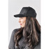 A black cap with a curved brim and adjustable strap, worn by a woman with long hair.