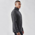 A man wearing a dark grey lightweight softshell jacket with a zip collar. The jacket features a logo.