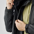 A close-up of a black jacket being unzipped, showcasing its interior lining and zip details.
