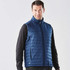 A navy quilted vest with a zip front, featuring a logo, worn over a black long-sleeve shirt.