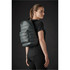 A quilted dark green backpack is worn on the back of a model in a black outfit, showcasing its sleek design.