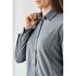 A grey button-up long sleeve shirt for women, featuring a collar and a chest pocket, with a logo visible.